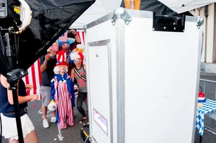 A family in patriotic costumes and props posing beside the open-air photo booth