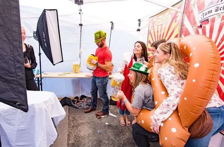 Guests with a giant inflatable pretzel and props at a Zum Schneider Oktoberfest photo booth